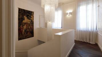A staircase with a white railing, a decorative chandelier, and a painting on the wall.