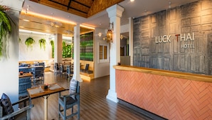 A hotel lobby with a reception desk, seating area, and a bar. - Luck Thai Hotel (Chiang Mai)