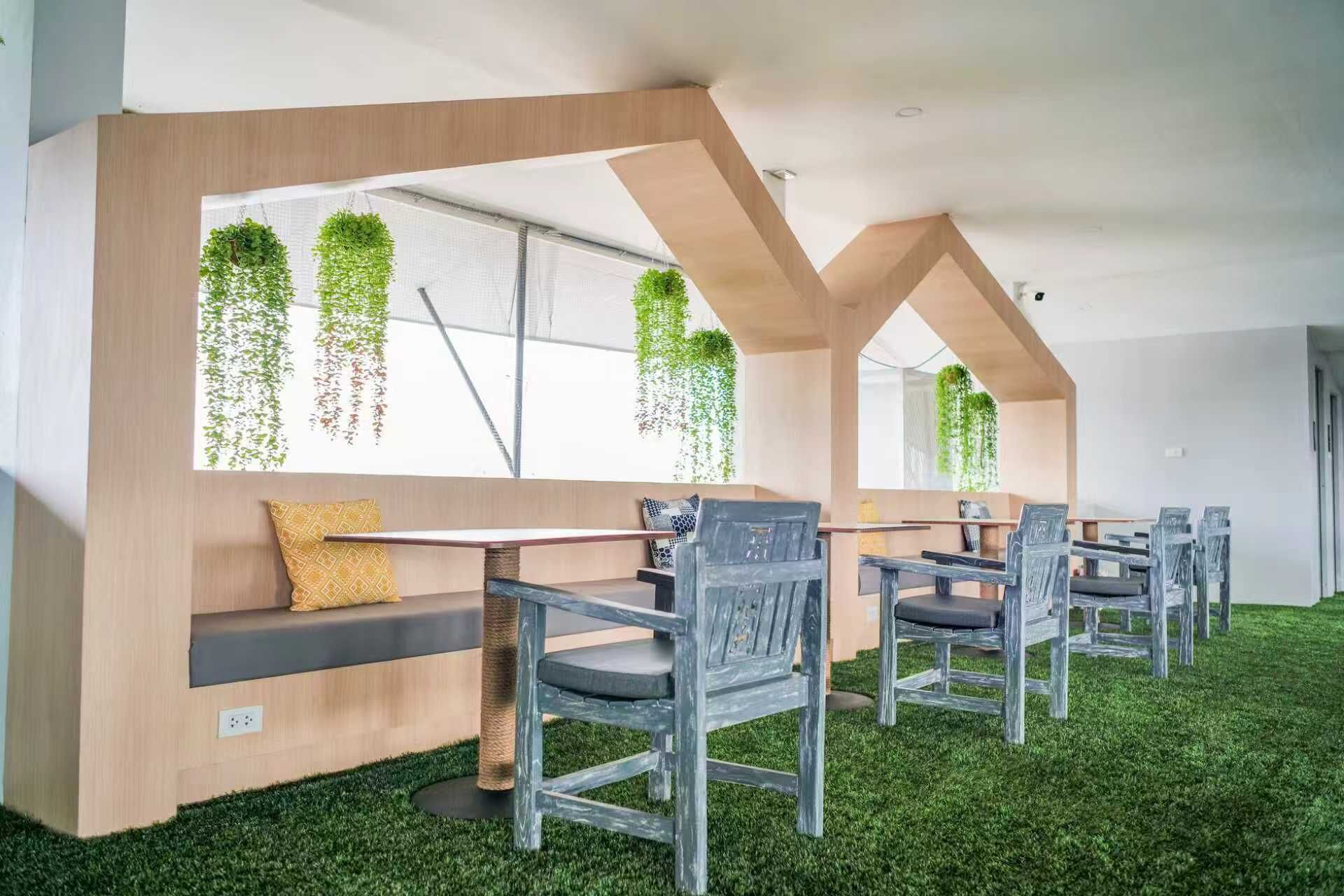 Un intérieur moderne avec une longue table et des chaises, un banc avec des coussins et un mur orné de plantes suspendues.