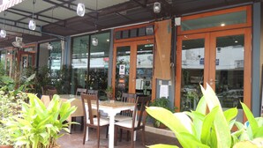 An outdoor seating area with tables and chairs, surrounded by potted plants. - Misone Hotel (Chiang Mai)