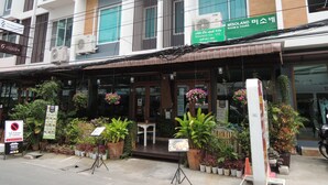 A building with a green sign for Misoland Co., Ltd., a restaurant with outdoor seating, and a no parking sign. - Misone Hotel (Chiang Mai)