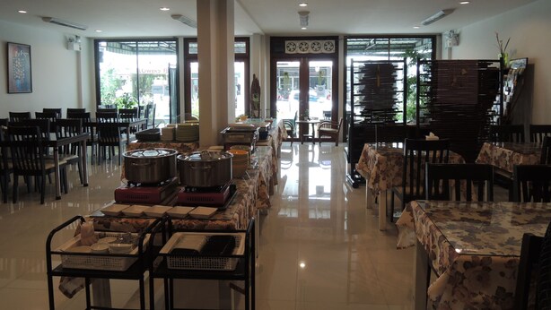 A spacious dining area with multiple tables and chairs, a buffet setup with food containers, and large windows allowing natural light. - Misone Hotel (Chiang Mai)