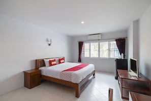 A bedroom with a bed, bedside table, desk, and TV.