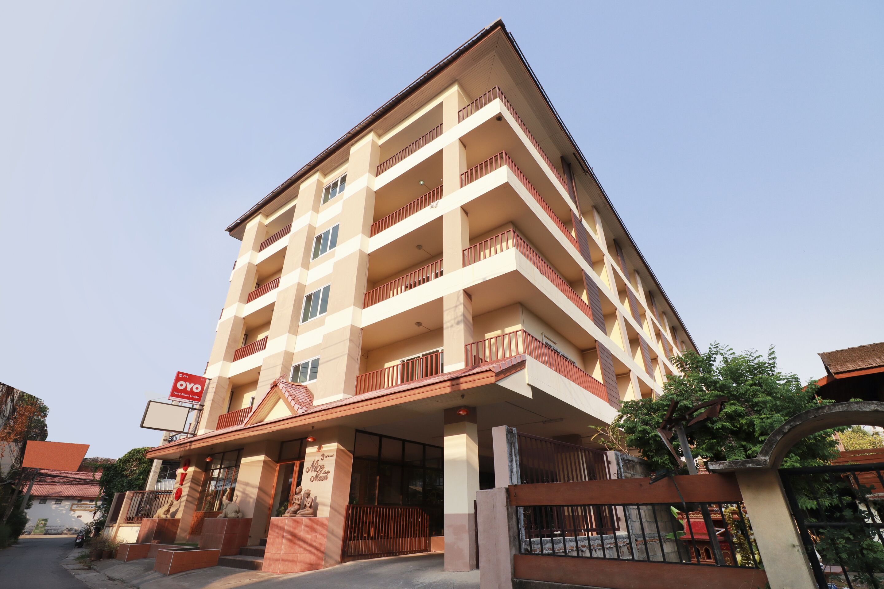 A multi-story hotel with a central entrance, balconies on each floor, and a sign indicating the name.