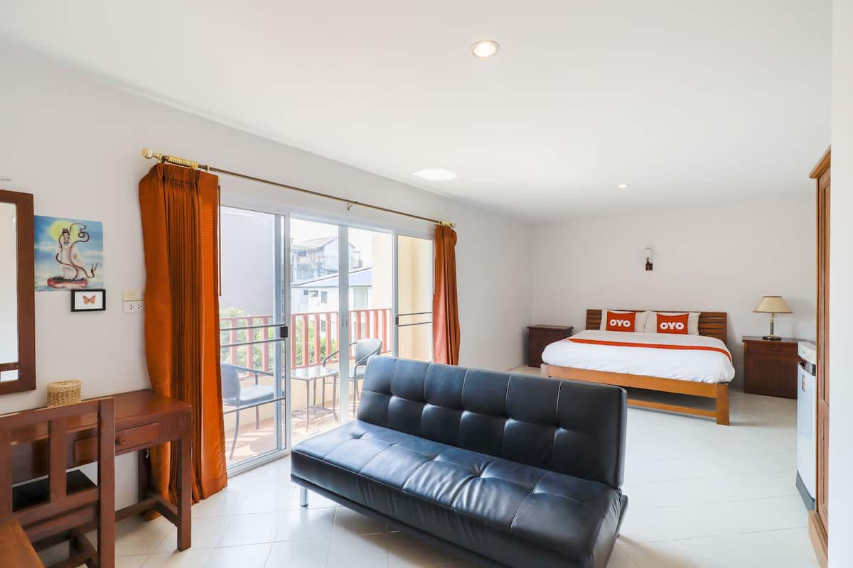 Una camera d'albergo con un letto, un divano, una scrivania e un balcone con vista.