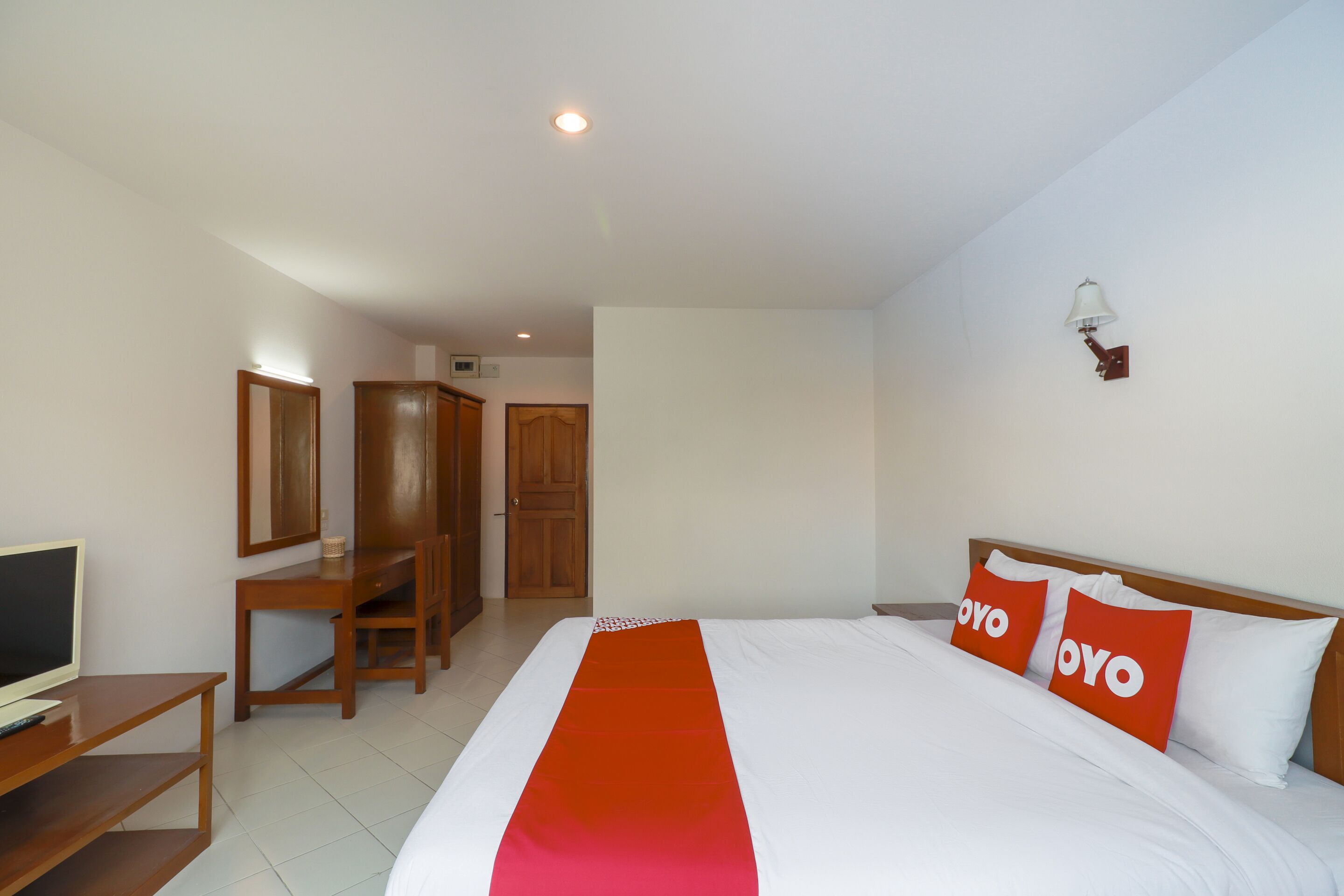 A hotel room with a bed, a desk, a TV, and a wardrobe.