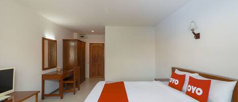 A hotel room with a bed, a desk, a TV, and a wardrobe.