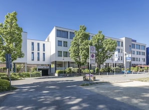 A modern hotel with a white facade, multiple windows, and a sign indicating a 20 km/h speed limit zone. - Best Western Hotel am Europaplatz (Koenigsbrunn)