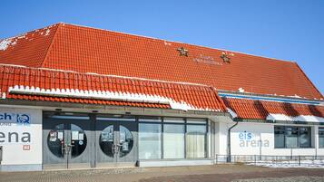 A building with a red-tiled roof, large windows, and signage for 'eis arena.'