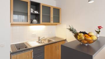 A kitchen with wooden cabinets, a stainless steel sink, and a fruit bowl on the counter.
