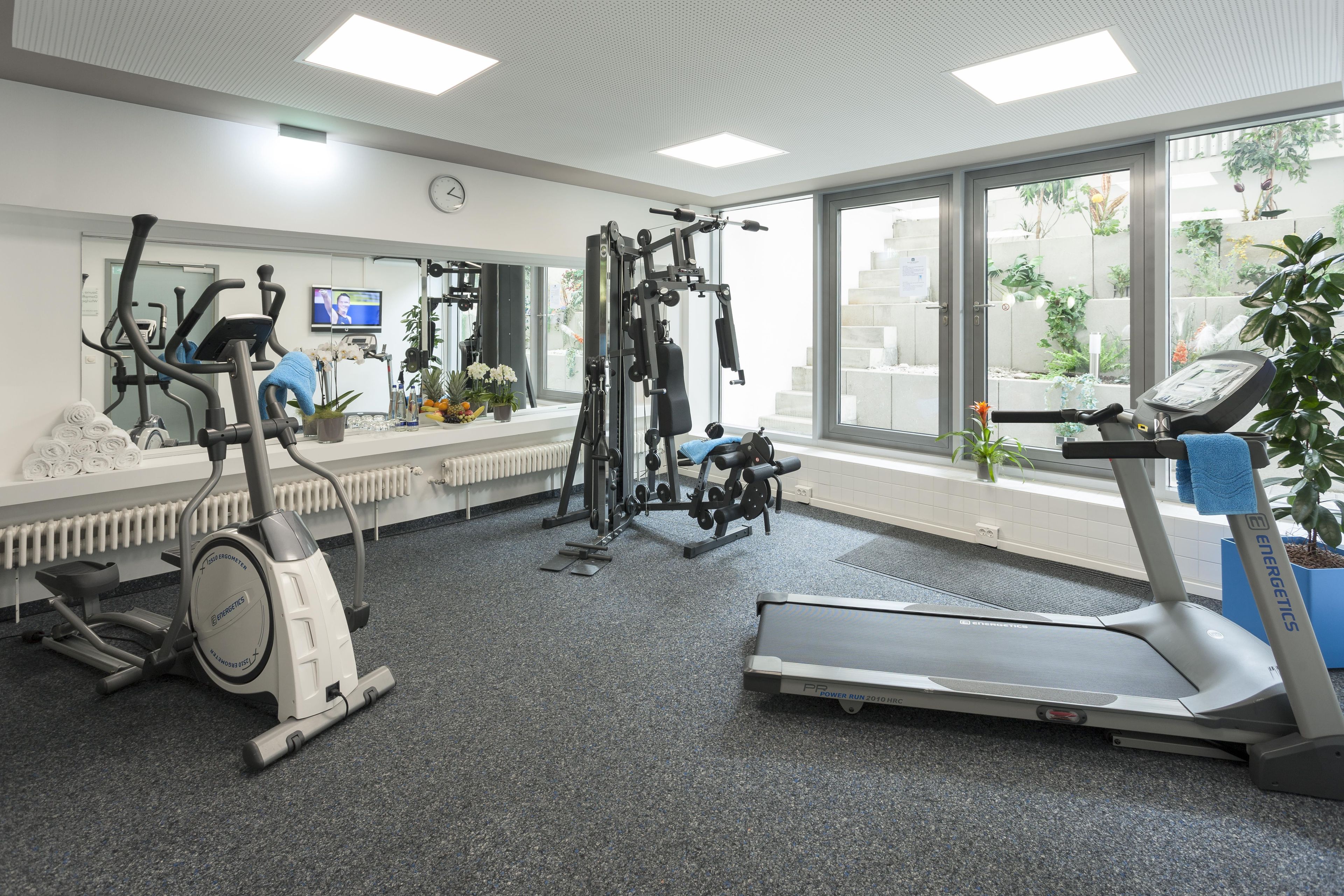 A gym with various exercise equipment, a large window, and a radiator.