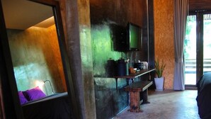 Ein modernes Wohnzimmer mit einem großen Spiegel, einem an der Wand befestigten Fernseher, einer Bank und einem Topfpflanzen.