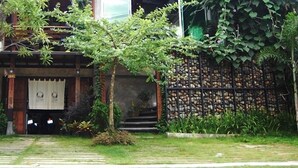 Ein traditionelles Haus mit einer Holzbalkonveranda, Blumentöpfen und einer Steinmauer.