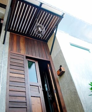 Una porta in legno con una finestra, un cancello in metallo e un piccolo faretto a parete.