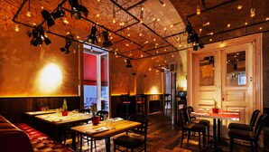 Ein Restaurant mit Holztischen und -stühlen, einer rot gepolsterten Bank und hängenden Lampen.
