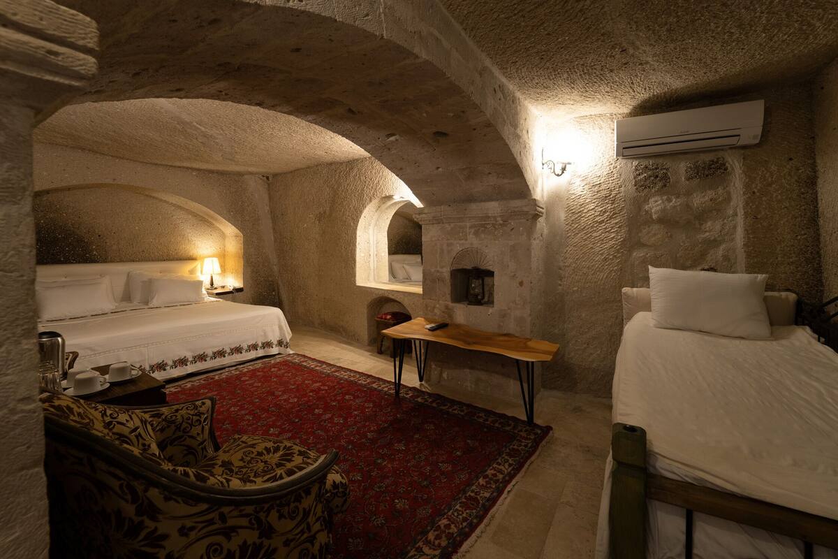 A room with a bed, a small table, a chair, and a red carpet.