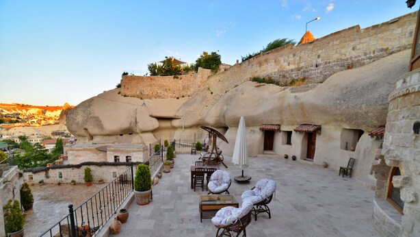 A rooftop terrace with stone walls, outdoor furniture, and potted plants. - Grand Cave Suites (Nevsehir)
