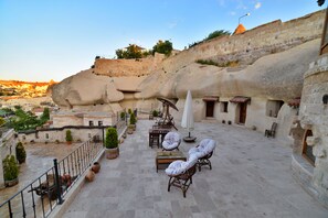Una terraza en la azotea con muros de piedra, mobiliario exterior y plantas en macetas.
