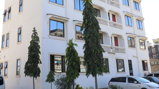 A multi-story building with a white facade, multiple balconies, and several windows.