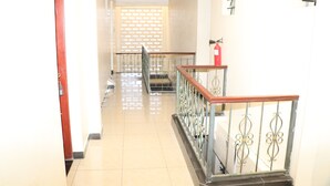 A hallway with a tiled floor, a wooden handrail, and a metal railing.