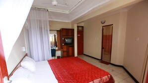 A hotel room with a bed, a television, a desk, and a wardrobe.