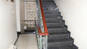 A staircase with a metal handrail and black steps, leading to a door with a decorative metal grille.