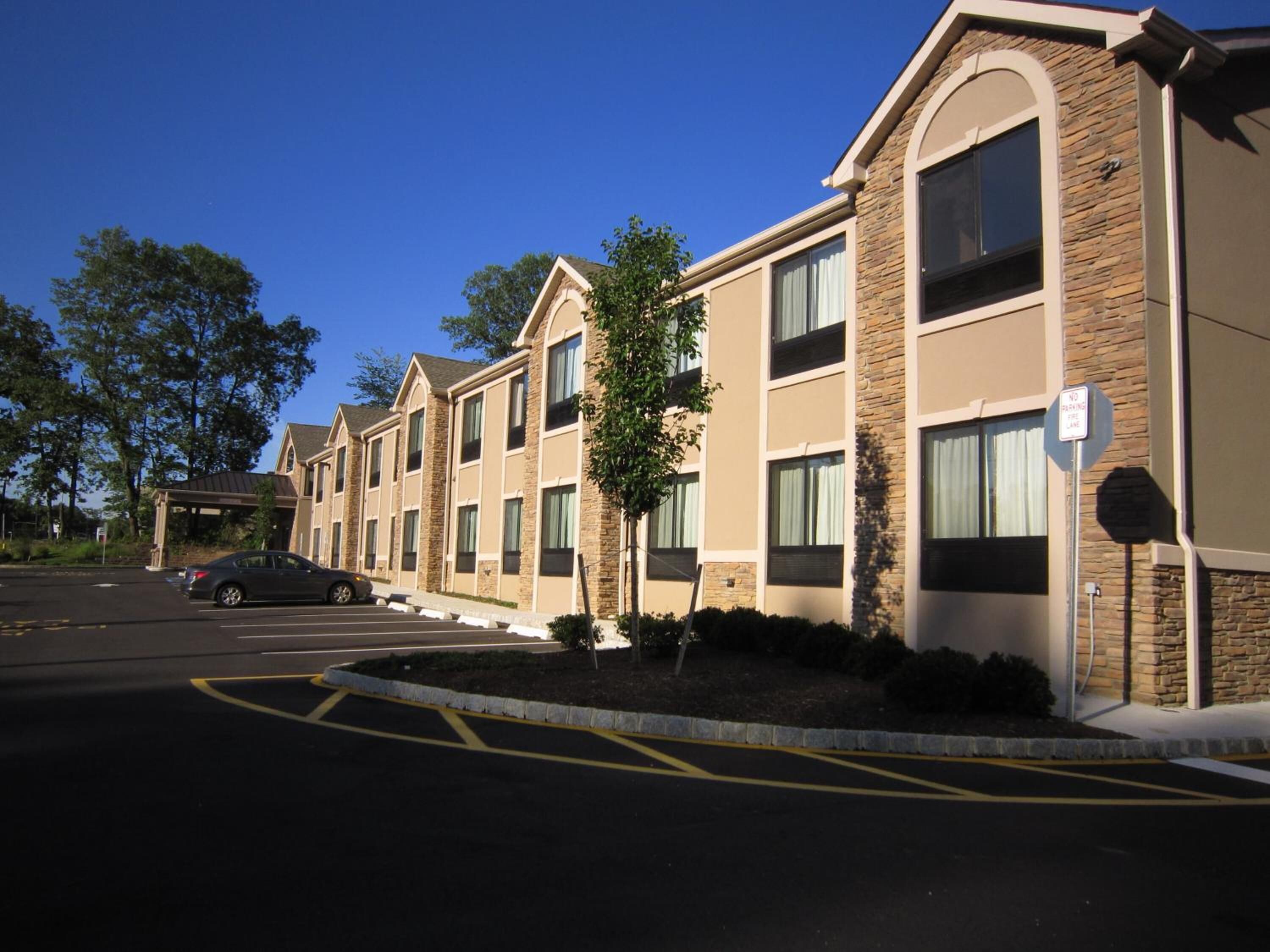 A row of modern hotel buildings with a parking lot in front.