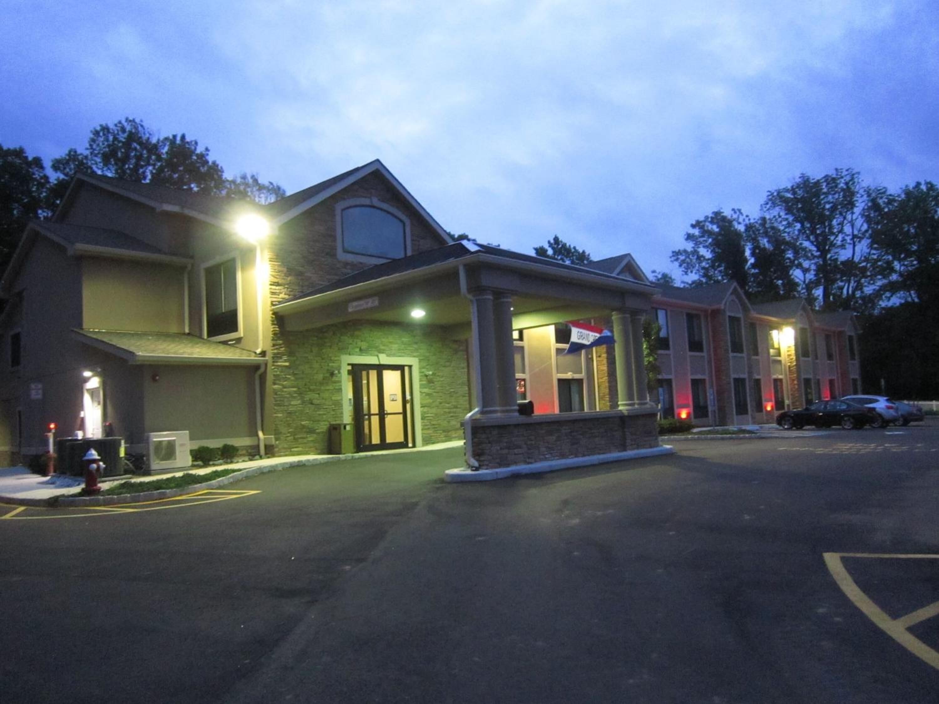A hotel with a stone facade, multiple stories, and a parking lot.