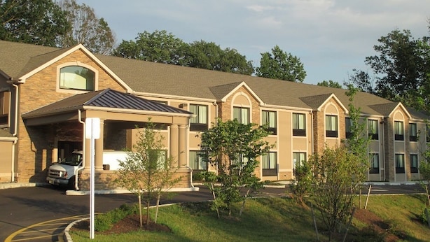 A hotel with a brick facade, multiple windows, and a covered parking area.