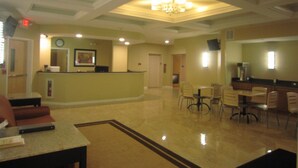 A hotel lobby with a reception desk, seating area, and a chandelier.