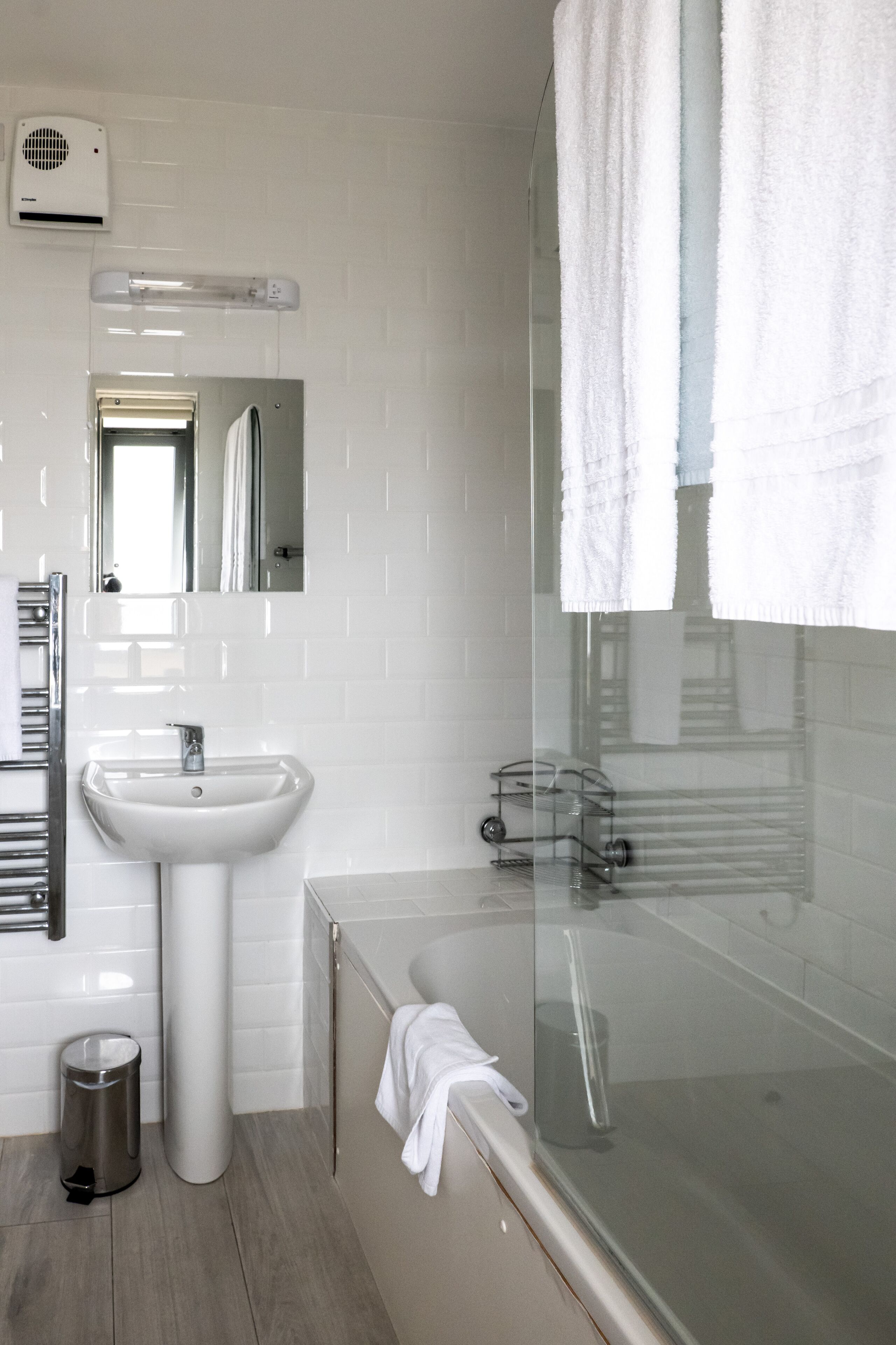 A modern bathroom with a glass-enclosed shower, a white sink, and a mirror above it.