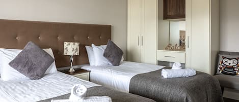 A hotel room with two beds, a wardrobe, a nightstand, and a mirror.