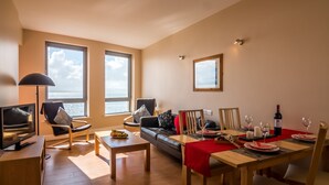 Ein modernes Wohnzimmer mit Essbereich, großen Fenstern und Meerblick.