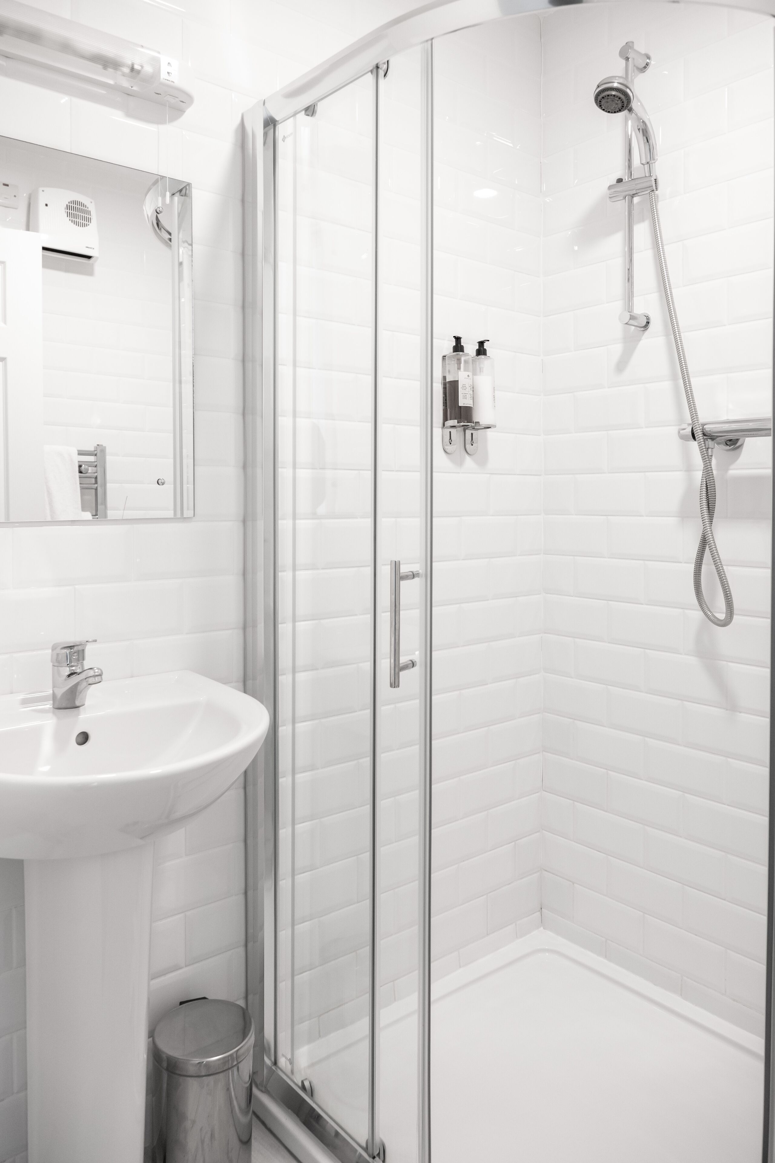 A modern bathroom with a glass-enclosed shower, a white sink, and a mirror.