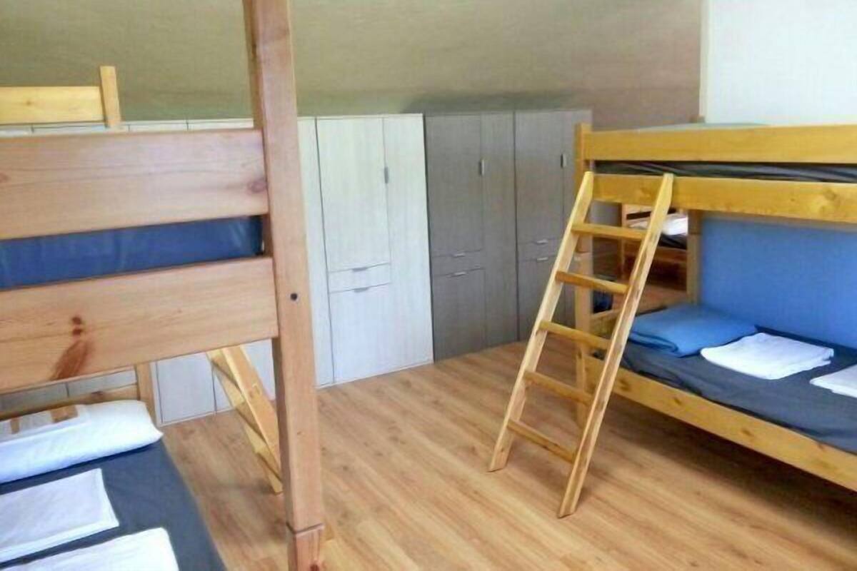 A dormitory room with bunk beds, a wardrobe, and a ladder.