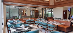 Un restaurante con cabinas y mesas, ventanas amplias y vistas al exterior.
