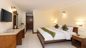 A hotel room with a bed, bedside tables, a desk, a television, and a door leading to another room. - juSTa Riverside Resort - Srinagar (Devaprayag)