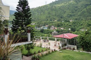 A resort with a terrace, potted plants, and a view of a lush green valley.