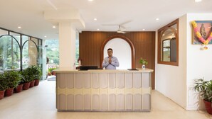 A reception desk with a modern design, a ceiling fan, and potted plants. - juSTa Riverside Resort - Srinagar (Devaprayag)