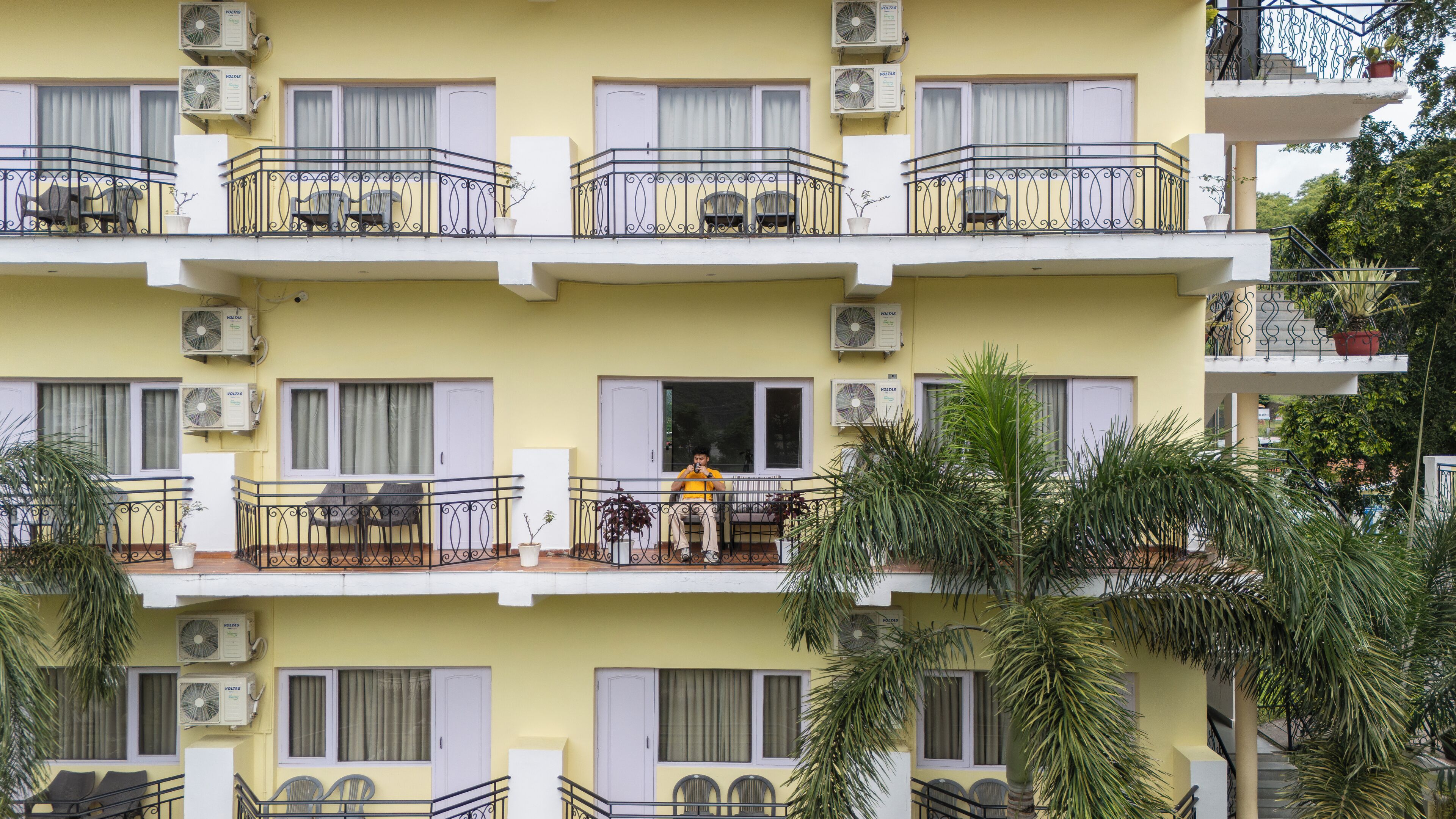 Un edificio a più piani con balconi, condizionatori e piante in vaso.