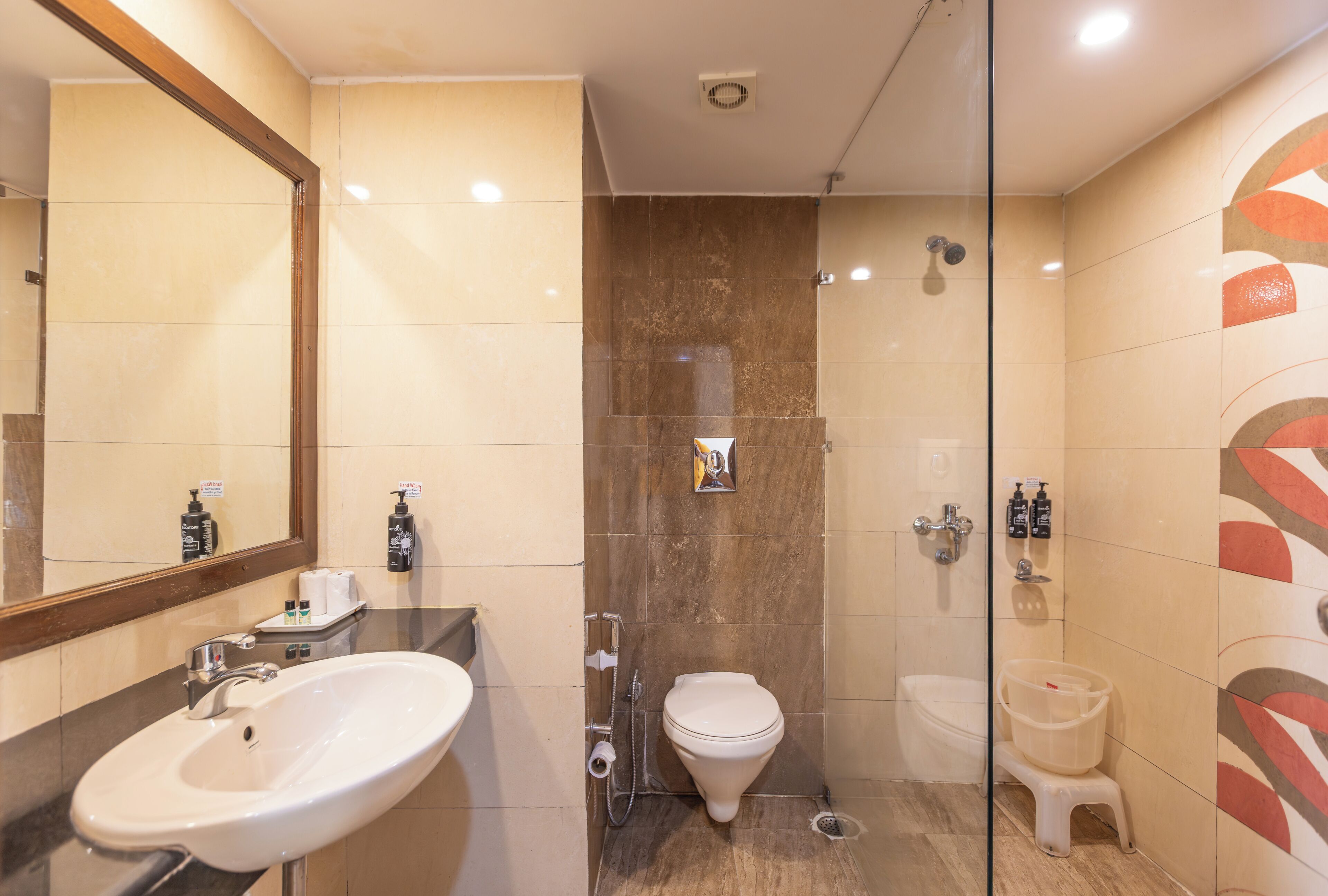 Un baño moderno con lavamanos, inodoro, ducha y espejo.