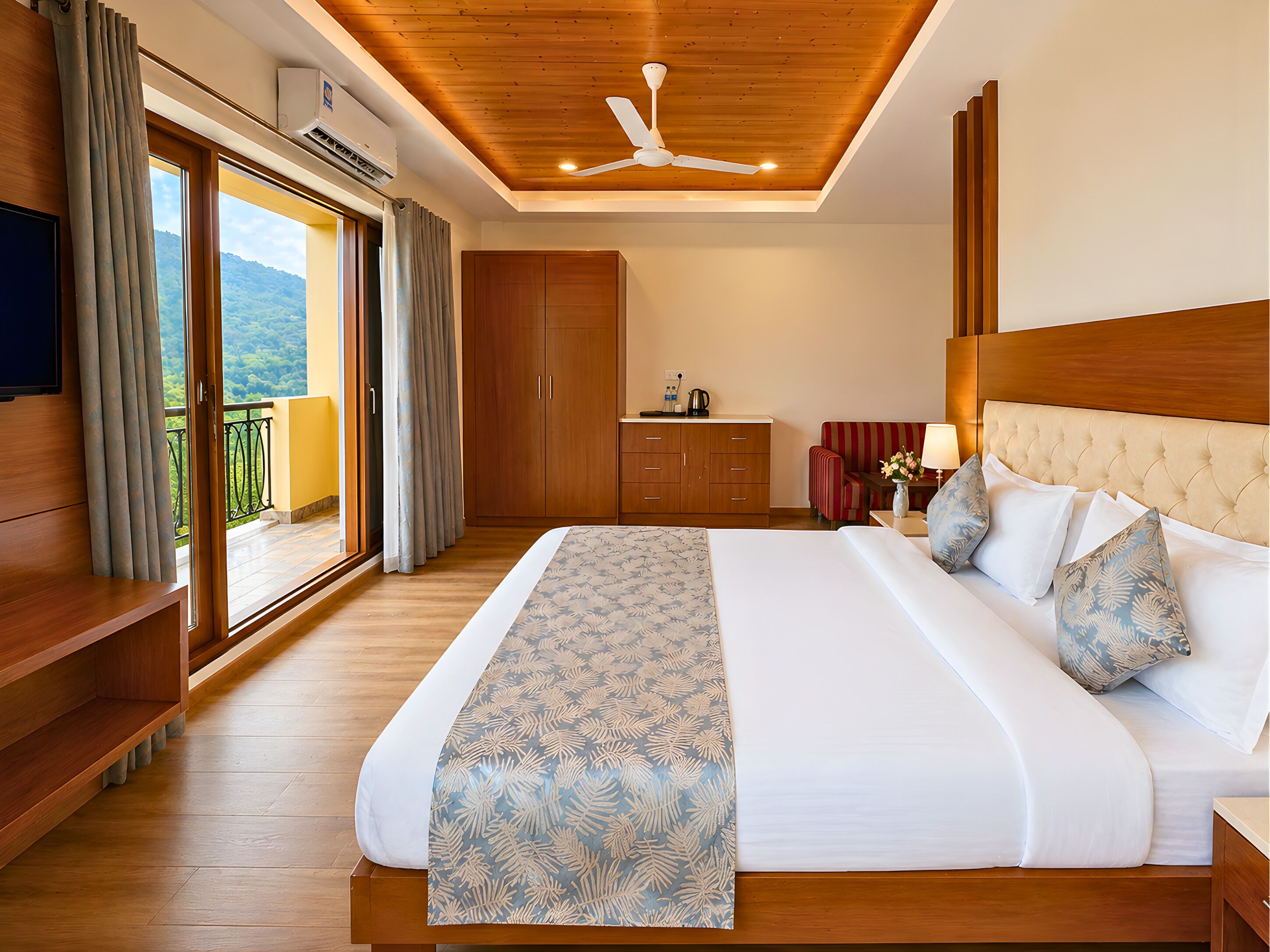 A hotel room with a large bed, a wooden ceiling, a wardrobe, a desk, and a view of the outdoors.