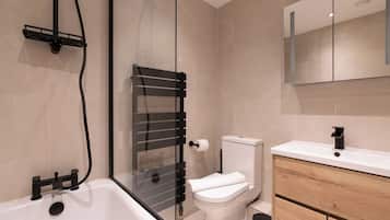A modern bathroom with a glass-enclosed shower, a white toilet, and a wooden vanity with a mirror.