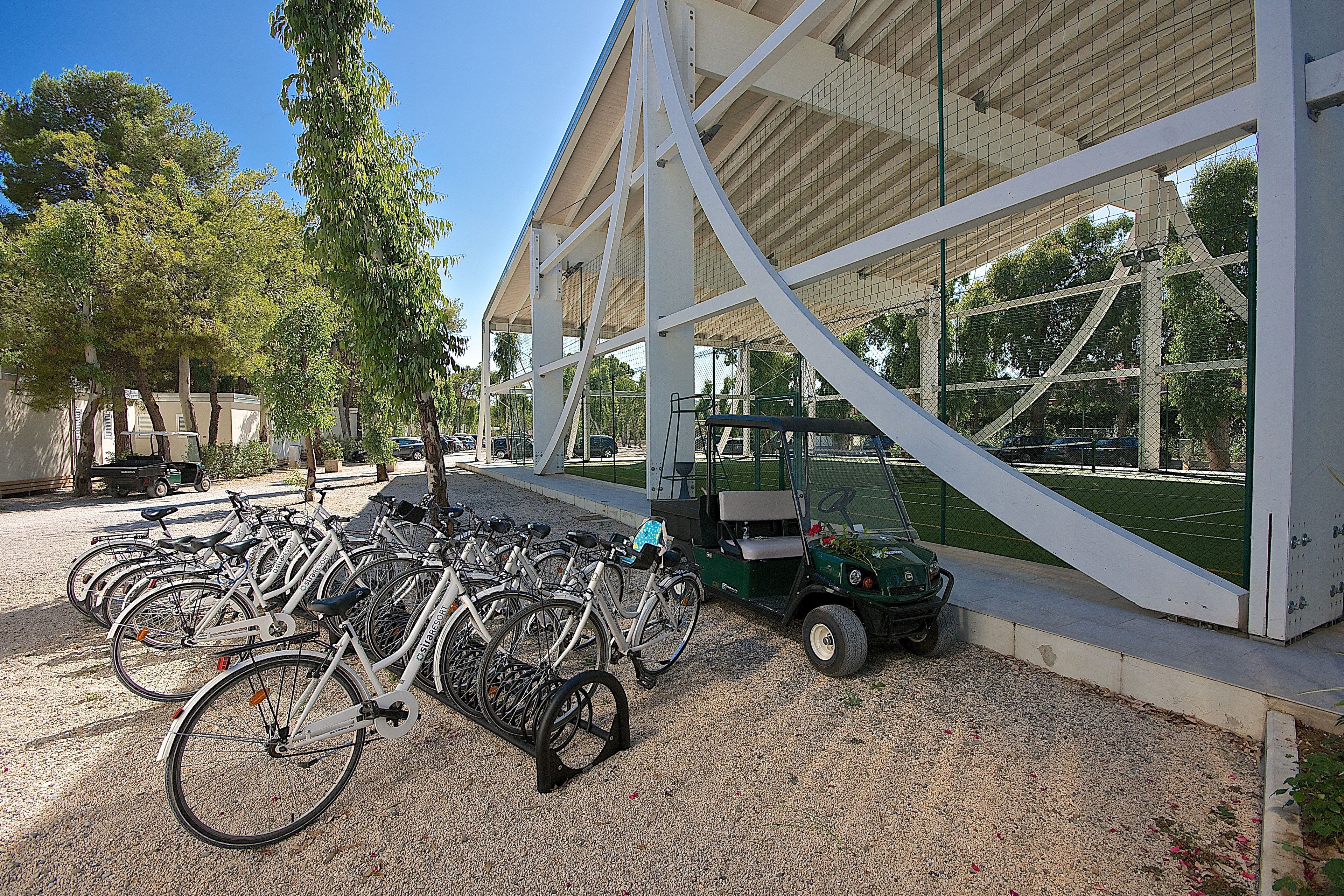 Un'area coperta per il parcheggio di biciclette, con biciclette e un golf cart.