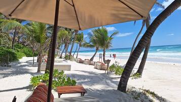 Playa privada, playa de arena blanca, camastros y sombrillas
