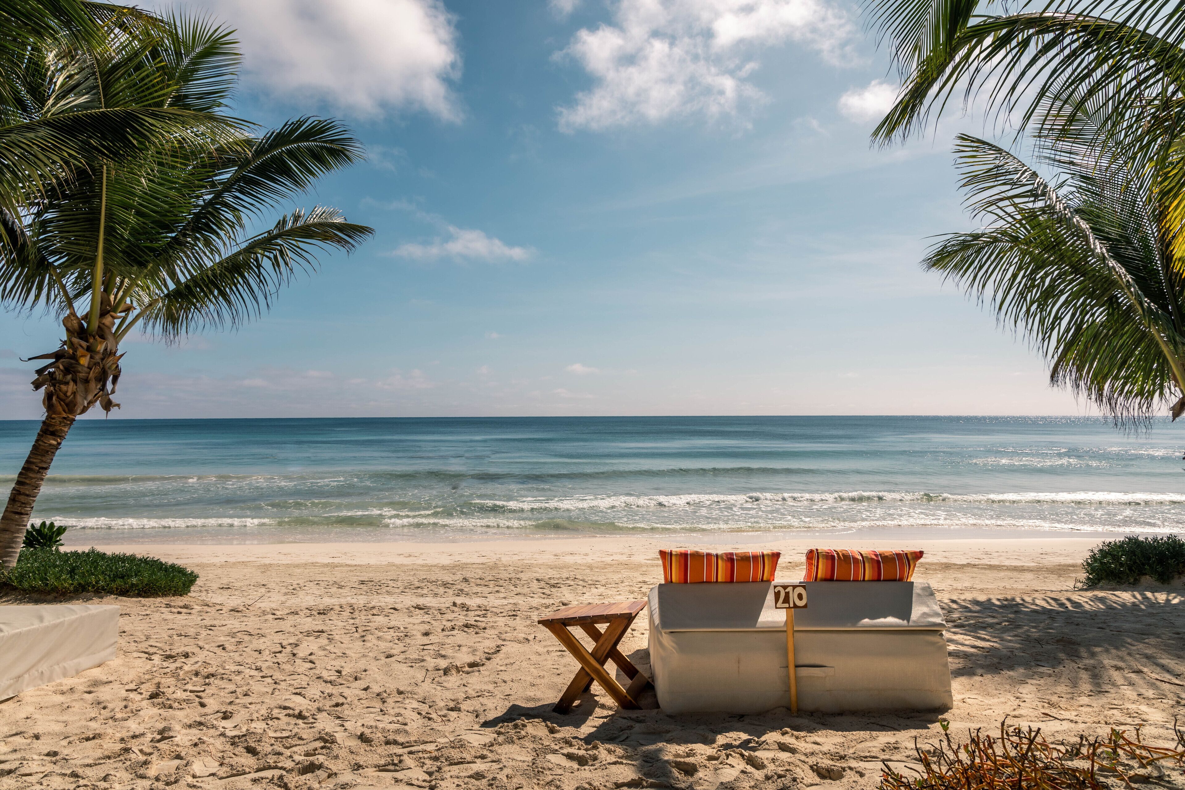 Een privéstrand, wit zand, ligstoelen aan het strand, parasols