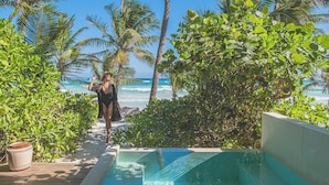 A pool area with a view of the ocean, surrounded by lush greenery and palm trees. - The Beach Tulum Hotel (Tulum)