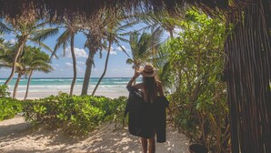 A wooden deck overlooking a beach with palm trees and a clear view of the ocean. - The Beach Tulum Hotel (Tulum)