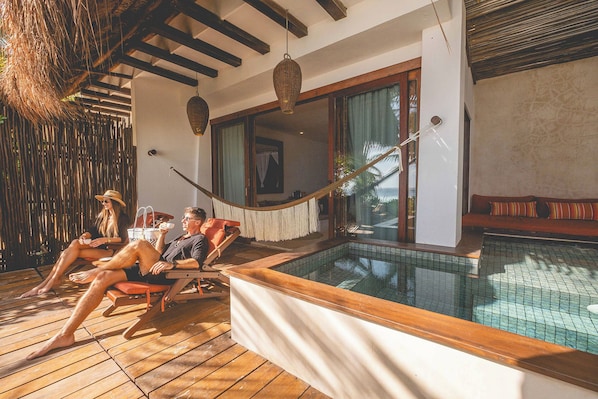 A poolside area with wooden flooring, a hammock, and a view of the ocean. - The Beach Tulum Hotel (Tulum)