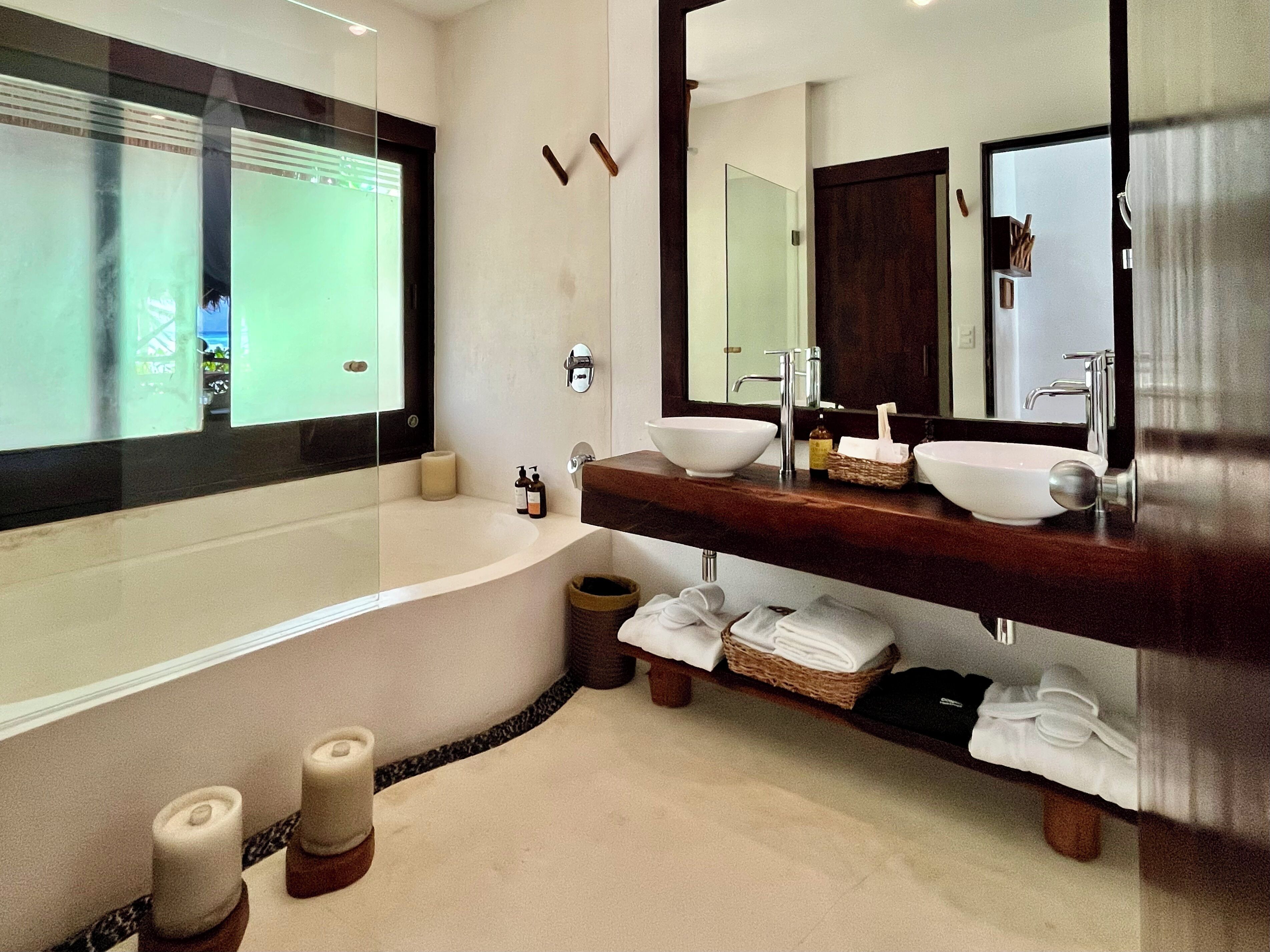 A modern bathroom with a large bathtub, two sinks, and a vanity with a mirror.